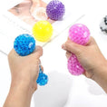 Load image into Gallery viewer, DIY Stress Ball Kit showing hands squeezing colorful custom stress-relief balls made with water beads.